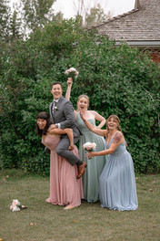 Groom on the back of a bridesmaid and the other brides maids making funny faces