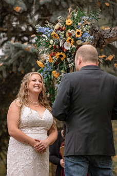 Bride and groom sharing an emotional ceremony moment beneath a rustic floral arch at the Strathmore wedding venue surrounded by romantic fall wedding details and autumn scenery.