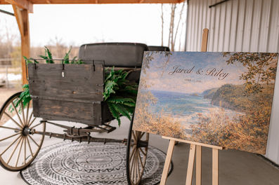 Rustic wagon and landscape painting display at a Cork and Crate wedding venue.