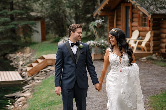 Bride holding her train in ne hand and holding grooms hand in other hand looking at eachother smiling