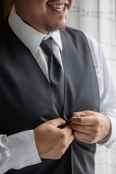 groom buttoning vest close up 