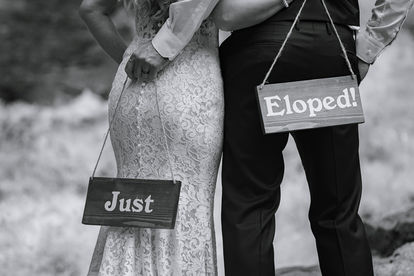 Close up of a bride and groom holding "Just Eloped" signs during an intimate Fernie wedding on their Crowsnest Pass wedding day