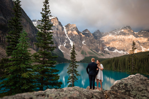Bride facing the groom as he looks at her the beautiful lake and mountains are in the background.