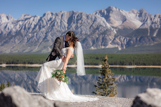 Bride and Groom kiss infront of mountain lake