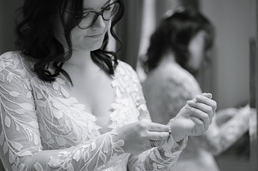 bride doing up her long sleeved wedding gown