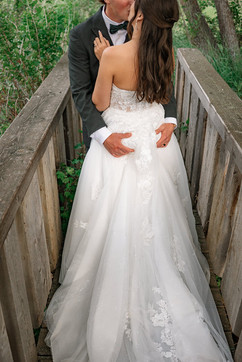 Close-up of the bride and groom sharing a kiss on a wooden bridge, captured in color by a Southern Alberta wedding photographer.