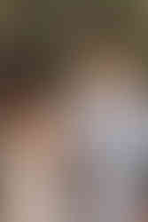 a bride reads her vows to her groom outdoors, the groom smiling warmly at her during their intimate mountain ceremony