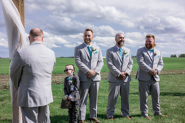 Groom stands at alter with groomsmen and ring bearer 
