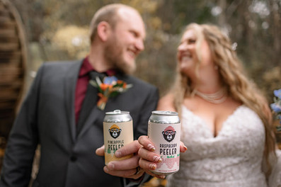 Strathmore photographer capturing a fun bride and groom portrait holding local drinks during a rustic fall wedding filled with candid moments and autumn countryside vibes.