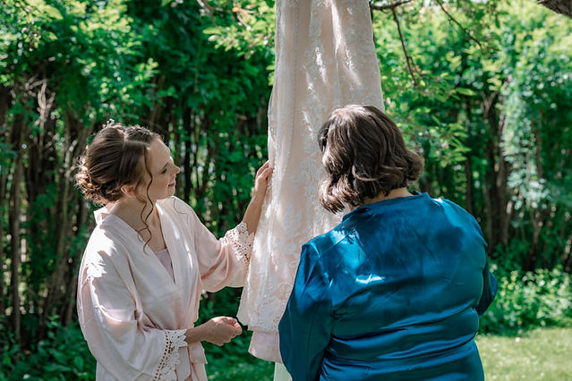 bride taking in her wedding dress prior to putting it on with her mom