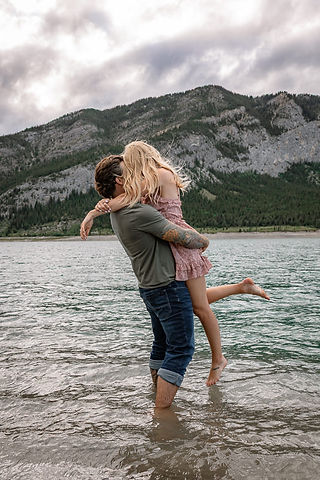 Newly engaged couple celebrating in the water following a surprise proposal, photographed by a Surprise Proposal Photographer in Alberta.