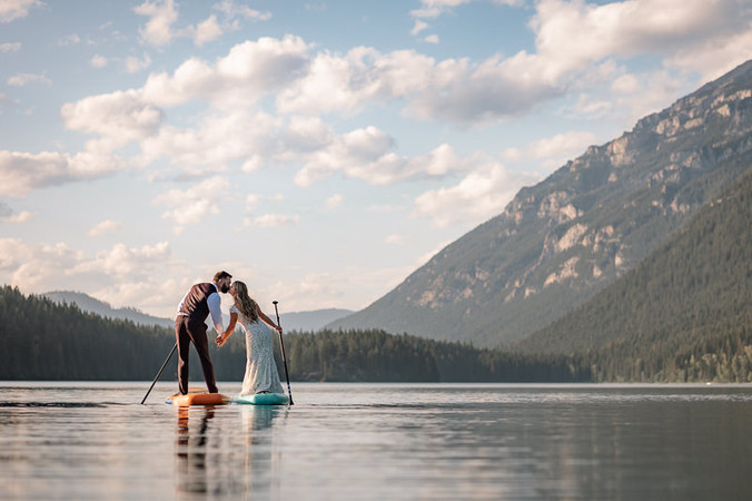 bride and groom kissing on paddleboard on a lake near fernie bc