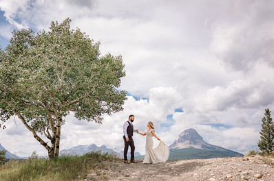 An intimate Southern Photographer captured the bride and groom standing beneath a tree overlooking the mountains on their Crowsnest Pass wedding day