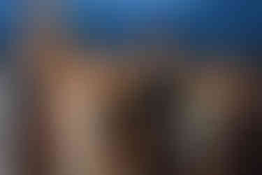 Bride and groom smiling and holding hands on the dance floor as guests cheer around them, captured by a Canmore Wedding Photographer.