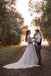 Groom kissing brides hands with sunset in the background 