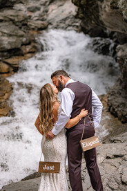 Bride and groom standing close together in front of a cascading waterfall during an intimate Fernie wedding on their Crowsnest Pass wedding day