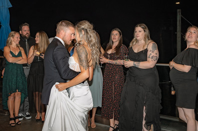 Newlyweds hold each other close during their first dance while friends and family look on, photographed by a Canmore Wedding Photographer.