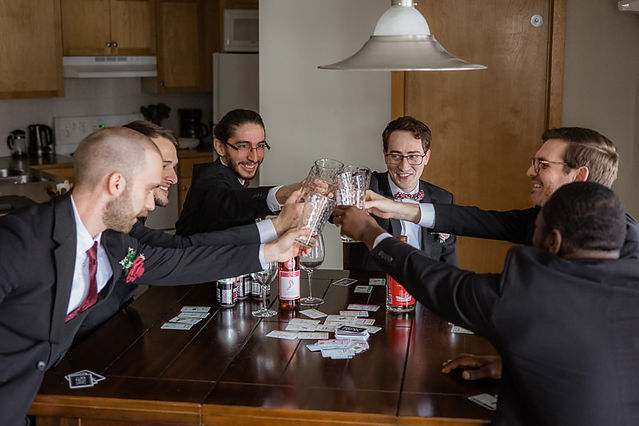 Groom and groomsmen cheering while playing cards