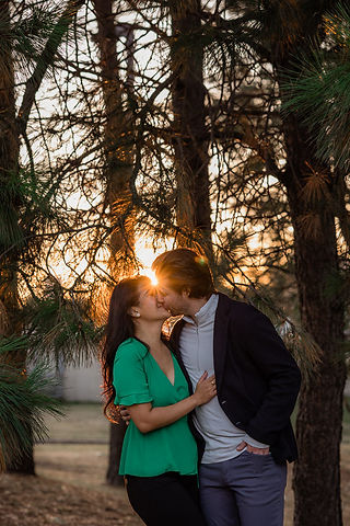 couple kiss with trees and sunlight in the back 