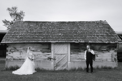 Black and white bride and groom looking at one another from either side of the rustic barn at Diamond in the Rough