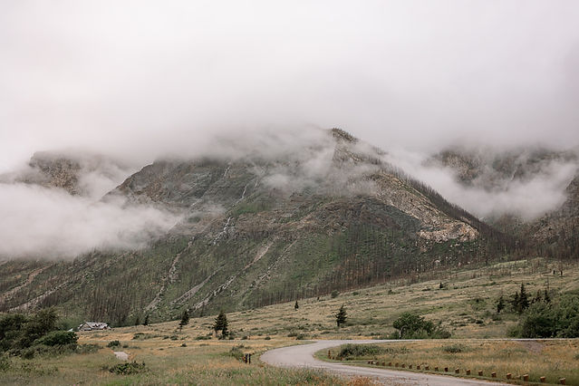 Mountain landscape with a winding road and misty clouds captured by a Waterton Park wedding photographer.