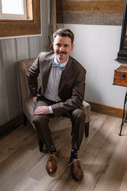 Groom seated in a rustic room while getting ready for a Cork and Crate wedding.