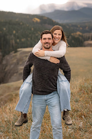 Couple doing a piggyback in a field during fun engagement ideas.