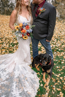 Bride and groom posing with their dog during a rustic fall wedding at the Strathmore wedding venue surrounded by autumn leaves and colourful countryside wedding florals.