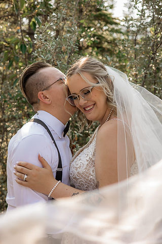 grooms whispers in bride's ear while she smiles 