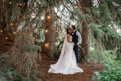 groom kissing bride under fairy lights