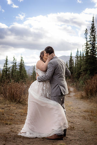 Bride and groom kissing as bride swooshes her dress