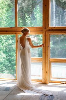 Bride standing by floor to ceiling windows at a Bragg Creek Airbnb wedding venue