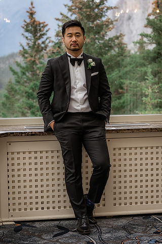 groom stands with hands in his pockets 