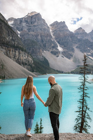 couple hold hands and look out over stunning lake