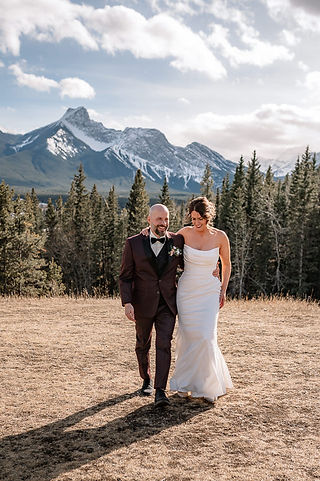 bride and groom walking walking together with snow capped mountains in the back