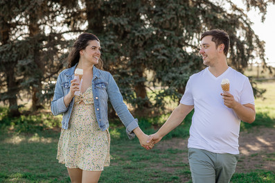 Samina and Sean hold hands while walking and enjoying their ice cream and looking at each other with smiles