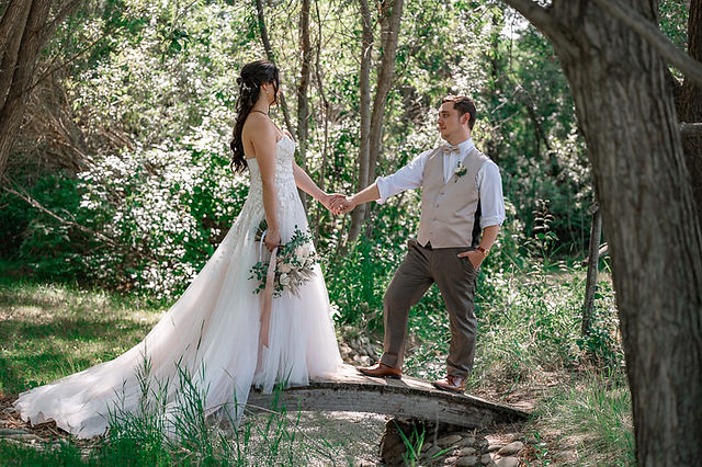 Bride and groom walking over a small bridge, groom helping bride