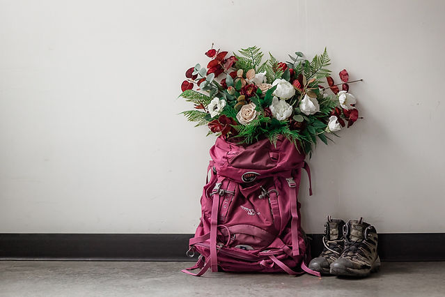 red fake flowers in pink back pack and hiking boots 