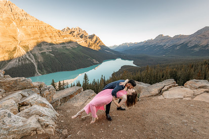 A newly engaged couple sharing a playful moment on a mountain overlook, photographed by a Banff Proposal Photographer