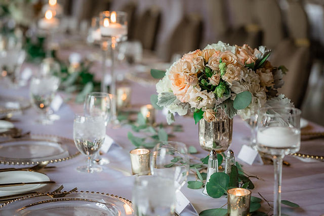 peach and white flower bouquets, foliage table runner, white tablecloth and floating candles 
