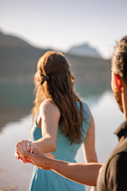 Couple handing hands at Bow Lake while looking out over the calm lake and mountains.