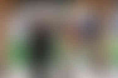  A groom spins his bride with his arm raised during their first dance under a rustic wooden gazebo, surrounded by guests at an outdoor wedding reception, captured by a Southern Alberta wedding photographer.