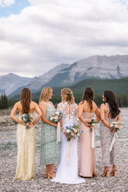 Bride and bridesmaids standing together with bouquets behind them and a mountain backdrop near their Kananaskis wedding
