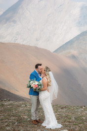 bride and groom kissing on mountain top