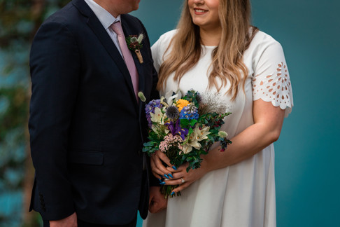 Bride and groom looking at one another. Showcasing their wedding attire and bouquet.