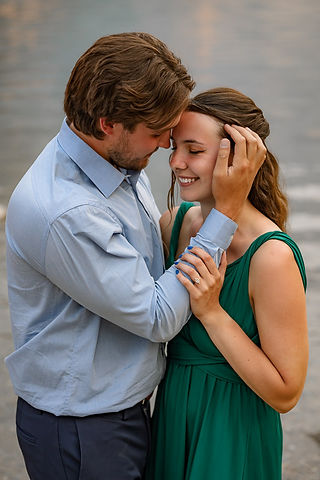 groom to be moves hair from fiance's face while she smiles 