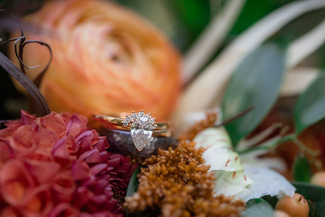 Macro shot of bride and grooms ring in fall coloured flowers