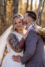 groom kisses bride in sunset