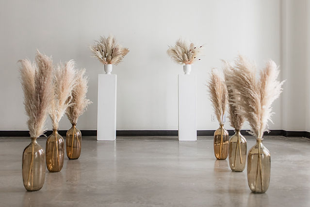 boho pampas flowers in vases and ontop of white pillars