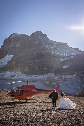 bride and groom run toward red helicopter 